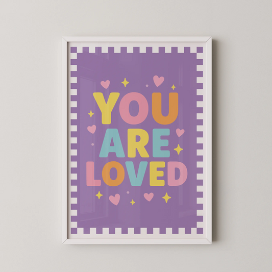 A modern typographic poster featuring the phrase "YOU ARE LOVED" in bold, rounded letters, surrounded by tiny hearts and sparkles on a soft pastel background.