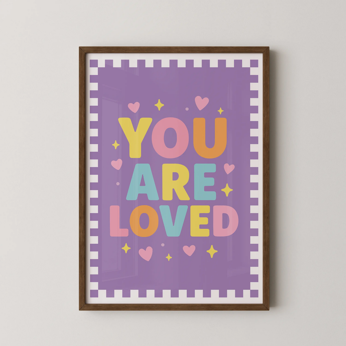 A modern typographic poster featuring the phrase "YOU ARE LOVED" in bold, rounded letters, surrounded by tiny hearts and sparkles on a soft pastel background.