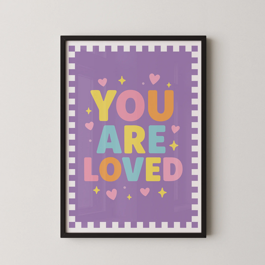A modern typographic poster featuring the phrase "YOU ARE LOVED" in bold, rounded letters, surrounded by tiny hearts and sparkles on a soft pastel background.